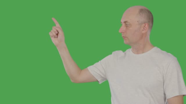 Caucasian-man-pointing-forefinger-for-showing-or-presenting-something-isolated-on-green-background.-1-2-3-point.-Alpha-channel,-keyed-green-screen