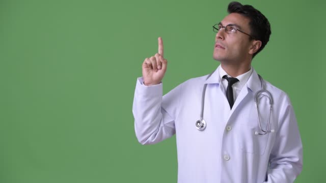 Young-handsome-Hispanic-man-doctor-against-green-background