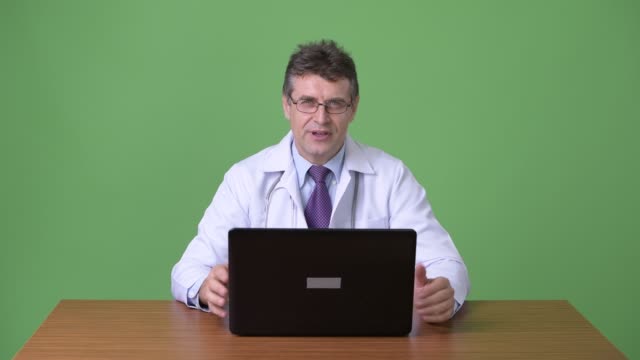 Mature-handsome-man-doctor-against-green-background