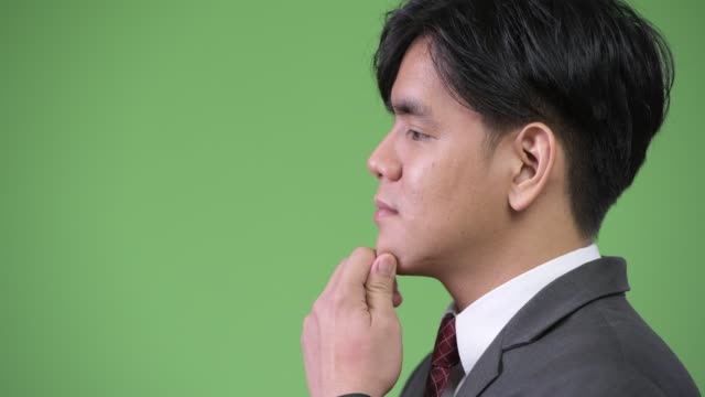 Young-handsome-Asian-businessman-against-green-background
