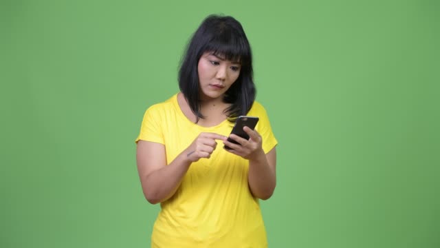 Schöne-asiatische-Frau-mit-Telefon-während-der-Suche-schockiert-betonte