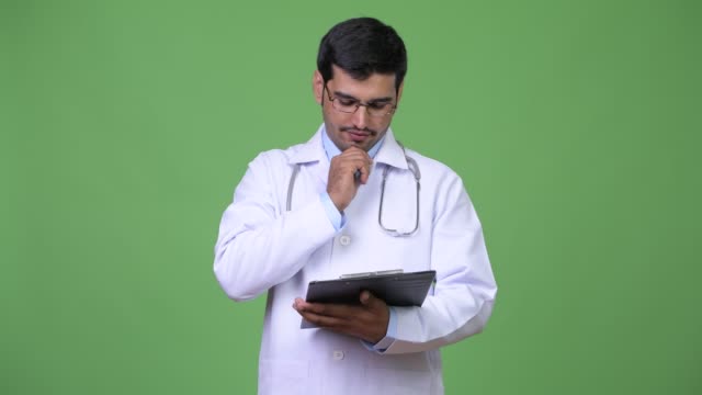 Young-handsome-Persian-man-doctor-reading-on-clipboard