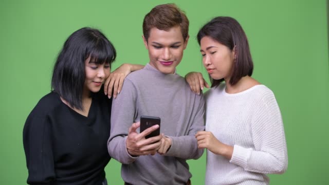 Drei-glückliche-asiatischen-Freunde-mit-Handy-zusammen