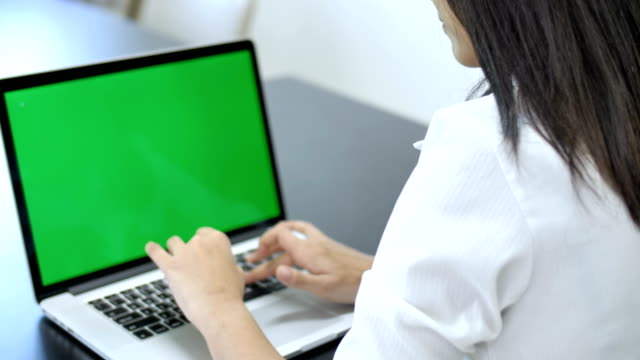 4K:-mujer-de-negocios-asiática-feliz-escribiendo-en-un-ordenador-portátil-con-una-pantalla-verde-clave