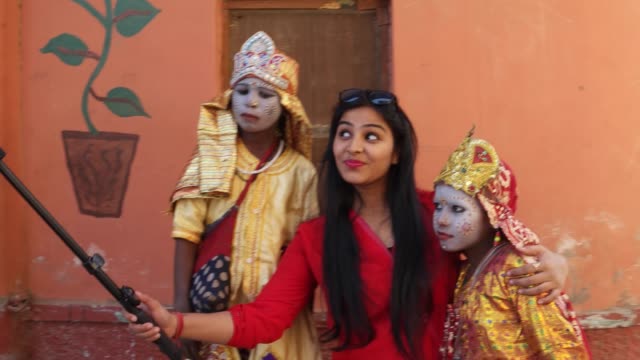 A-tourist-takes-selfies-photo-video-with-two-child-actors-in-goddess-make-up-with-a-smart-mobile-phone-camera-handheld