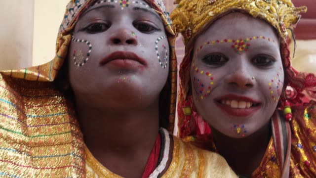 Handheld-Nahaufnahme-von-zwei-jungen-Mädchen-in-einer-indischen-Stadt-verkleidet-als-Göttin-für-Almosen-und-feiern-Göttlichkeit-und-segne-Touristen-Blick-auf-Kamera-und-Lächeln