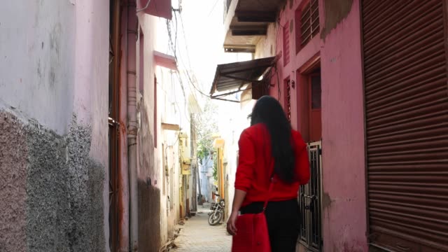 Indische-junge-weibliche-Touristen-durch-die-Straßen-kleine-Rampen-eng-Stadt-ländlichen-Einstellung-voll-gepackten,-handheld-folgen