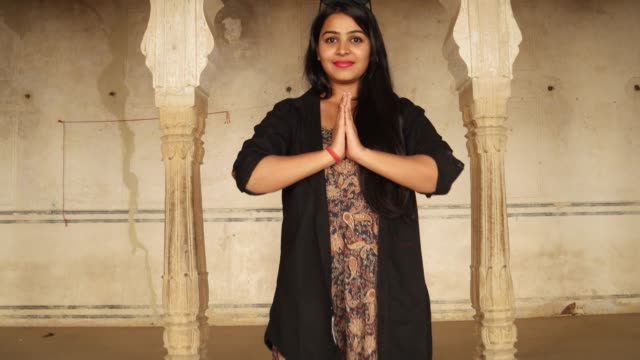 Handheld-POV-walk-to-Indian-woman-greets-namaste-joins-hands-welcomes-invites-joy-warm-temple-ancient-Indian-Hindu-traditional-architecture--black-hair-big-smile-happy-guest-home-interior-copy-space