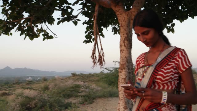 Handheld-shot-of-woman-texts-message-share-photo-video-smiles-mobile-phone-communicates-device-connectivity-signal-wireless-at-sunset-on-hill-outdoor-nature-hot-summer-magic-hour-beautiful-low-angle