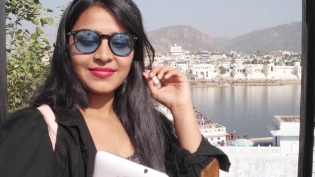 Mujer-mano-toma-selfie-foto-vídeo-con-su-dispositivo-celular-móvil-desde-un-punto-de-vista-de-vista-panorámica-de-Santo-lago-de-Pushkar,-una-ciudad-sagrada-para-el-festival-mela-de-peregrinos-hindúes-templos-de-ghats-de-baño