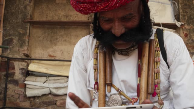 Hombre-ser-ayudado-e-instrucciones-para-utilizar-una-tableta-de-pantalla-táctil,-hombre-anciano-indio-de-Rajastán-con-bigote-grande-con-turbante-tradicional-de-la-vestimenta-y-la-ética