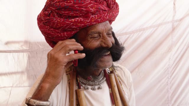 Mano-hombre-mayor-de-Rajasthani-en-una-conversación-móvil-del-teléfono-celular-inteligente