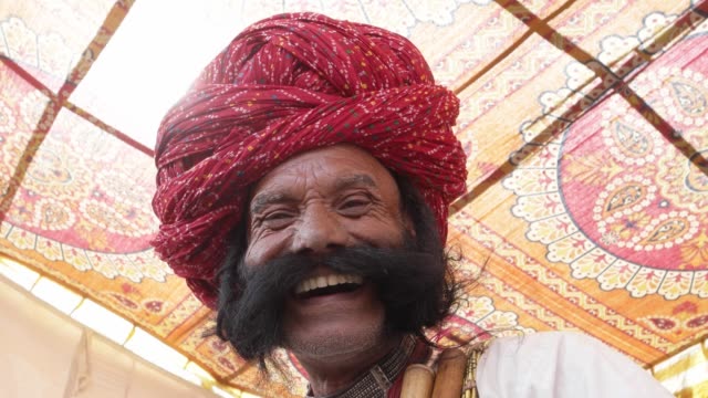 Handeln-und-lächelnd-indischen-Mann-aus-Rajasthan-mit-großen-Schnurrbart-tragen-ein-rotes-Turban-und-Tradition-Kleid