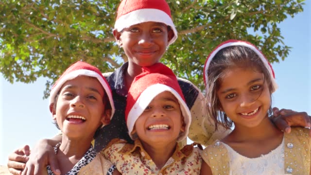 Kinder-Spaß-posiert-für-die-Kamera-mit-Santa-Hüte-mit-einem-Baum-im-Hintergrund