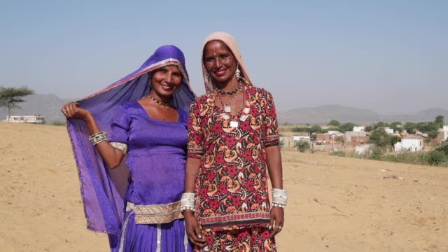 Tilt-up-to-two-friends-giggling-in-traditional-dress-in-deserts-of-Pushkar,-Rajasthan