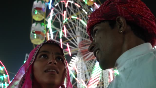 Indian-traditional-couple-talking-in-pink-sari-and-red-turban-at-Pushkar-Mela,-a-carnival-of-Rajasthan,-India