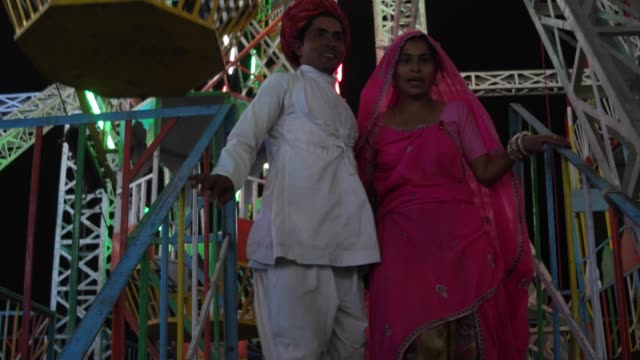 Pareja-India-goza-de-noria-paseo-en-vestidos-tradicionales-en-la-Pushkar-Mela,-un-carnaval-de-Rajasthán,-la-India