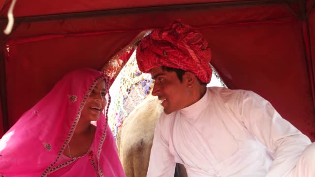 Tiro-mano-de-India-pareja-disfrutando-de-un-paseo-en-camello-en-una-caravana-en-la-Feria-de-Pushkar,-Rajasthan,-India