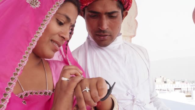 Indian-couple-sharing-a-smart-watch-and-discussing-showing-learning-health