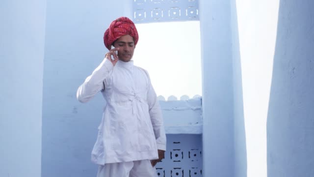 Tilt-down-to-a-handsome-man-in-traditional-Indian-turban-and-clothing-talking-on-the-phone-with-surreal-lighting