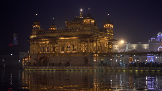 Video-of-Sikh-pilgrims-in-the-Golden-Temple-at-dusk-during-celebration-day-in-December-in-Amritsar,-Punjab,-India.-Harmandir-Sahib-is-the-holiest-pilgrim-site-for-the-Sikhs.