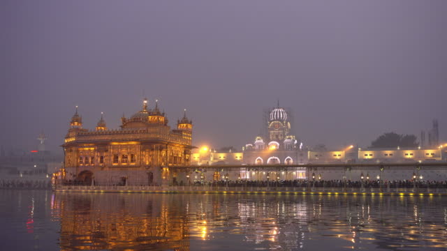 Video-de-peregrinos-sijs-en-el-templo-de-oro-al-atardecer-durante-el-día-de-la-celebración-en-diciembre-en-Amritsar,-Punjab,-India.-Harmandir-Sahib-es-el-sitio-más-sagrado-del-peregrino-para-los-Sikhs.