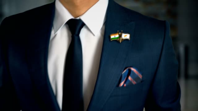 Businessman-Walking-Towards-Camera-With-Friend-Country-Flags-Pin-India---Cyprus