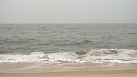 Waves-crashing-on-a-beautiful-beach-during-a-foggy-day-in-Varkala,-India.