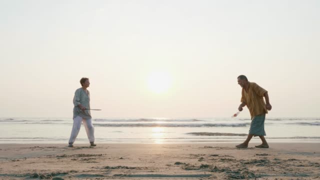 Active-senior-couple-playing-tai-chi-ballon-ball-at-the-beach.