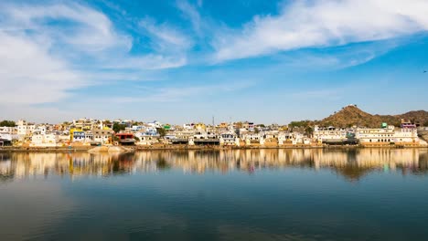 Time-lapse-at-the-holy-ghats-on-water-pond-in-Pushkar,-Rajasthan,-India,-sacred-town-for-hindu-people.-Moving-clouds-over-temples,-buildings-and-ghats.