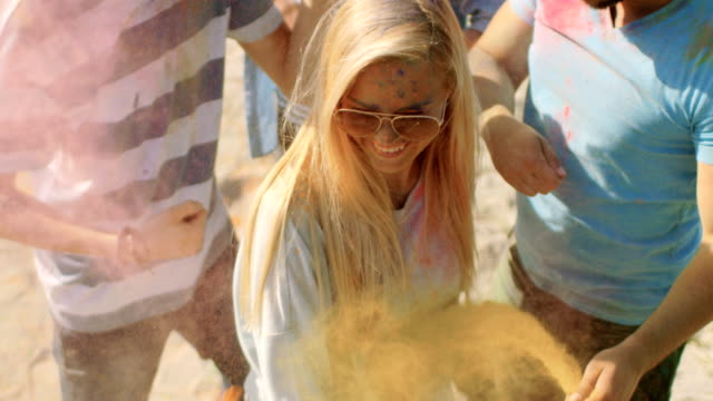 High-Angle-Shot-von-einem-blonden-Mädchen-werfen-bunte-Pulver-in-die-Menschenmenge-inmitten-hinduistischen-Holi-Fest-feiern.-Sie-haben-enorm-viel-Spaß-an-diesem-sonnigen-Tag.