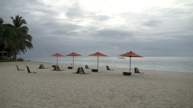 Am-Meer-am-Strand-stehen-Liegestühle-mit-Sonnenschirmen