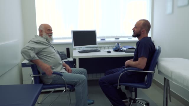 Arzt-im-Gespräch-mit-älteren-Mann-im-Büro