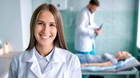 Sonriente-a-mujer-doctor-en-bata-blanca-con-paciente-preparación-de-tablet-PC-para-el-procedimiento