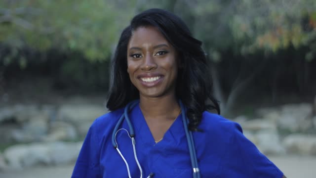 Schöne-schwarze-Krankenschwester-in-Scrubs-lächelnd-in-die-Kamera