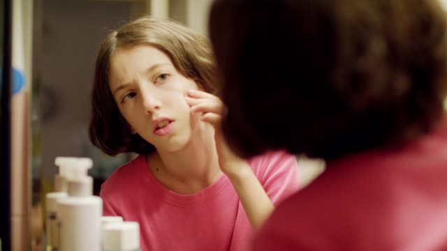 Teenager-Mädchen-auf-der-Suche-der-Überprüfung-ihr-Gesicht-Badezimmerspiegel