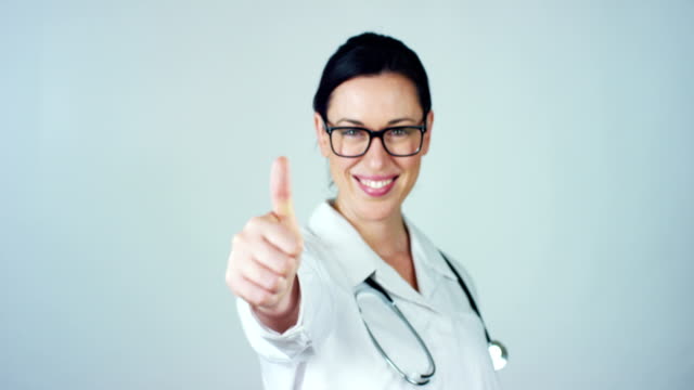 Portrait-of-a-female-doctor-with-white-coat-and-stethoscope-smiling-looking-into-camera-on-white-background.