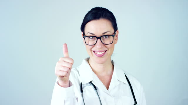 Portrait-of-a-female-doctor-with-white-coat-and-stethoscope-smiling-looking-into-camera-on-white-background.