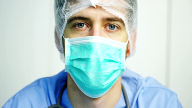 Porträt-eines-Chirurgen-oder-Arzt-mit-Maske-und-Kopfhörer-bereit-für-den-Einsatz-im-Krankenhaus-oder-einer-Klinik-in-der-Nähe.-Der-Chirurg-lächelt-sicher-und-stolz-auf-sich.