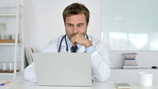 Pensive-Doctor-Thinking-and-Working-on-Laptop