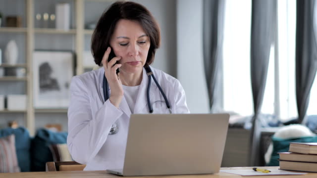 Vieja-señora-médico-discutir-con-el-paciente-durante-la-conversación-de-teléfono