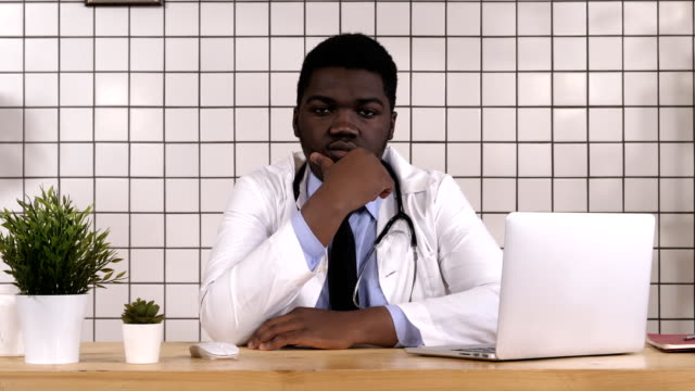 Médico-afroamericano-mirando-serio-al-pensamiento-de-cámara
