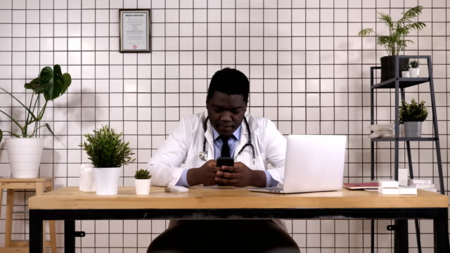 Africano-americano-Doctor-Holding-Smart-teléfono-mensajes-de-texto