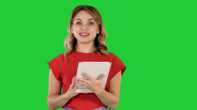 Mujer-presentadora-de-camiseta-rojo-sosteniendo-un-tablet-da-vuelta-páginas-y-hablando-a-la-cámara-en-una-pantalla-verde-Chroma-Key