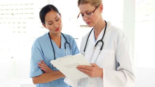 Medical-workers-looking-over-a-file-and-looking-at-camera
