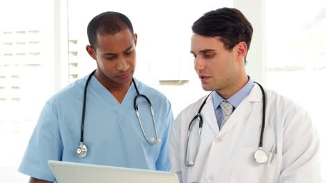 Medical-workers-looking-over-file-on-clipboard