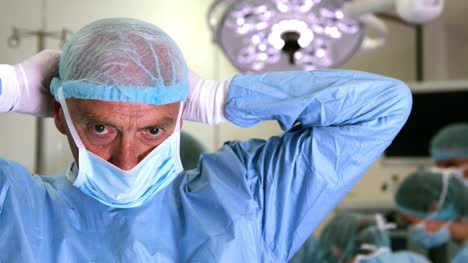 Medizinische-professor-in-Chirurgische-Ausrüstung-putting-auf-Maske