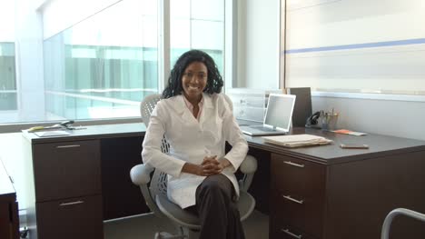 Portrait-Of-Female-Doctor-Working-At-Desk-In-Office