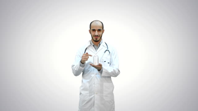 Lächelnde-Arzt-empfehlen-Pillen-und-zeigen-einen-Daumen-auf-weißem-Hintergrund
