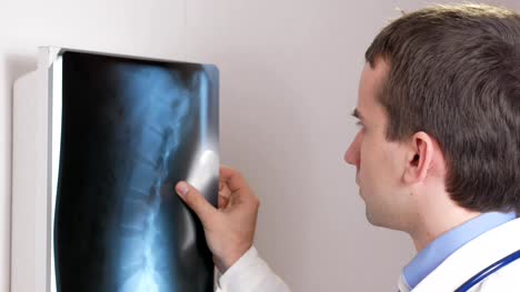 A-young-doctor-examines-the-results-of-a-patient's-X-ray-on-the-wall.-Analyzes-of-the-thorax-and-ribs